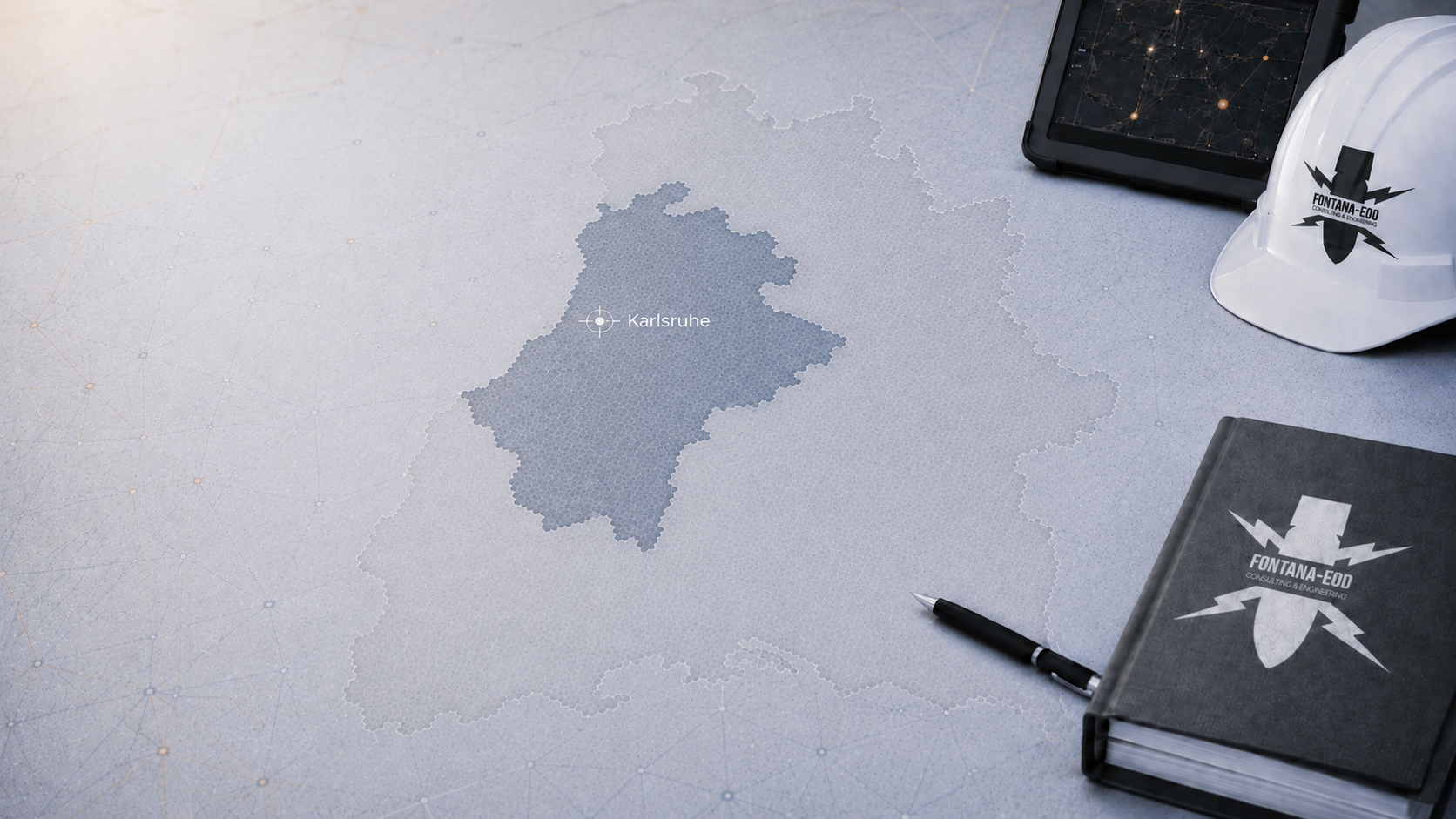Schematische Karte mit Markierung Karlsruhe, daneben Tablet, weißer Schutzhelm, Stift und Notizbuch.